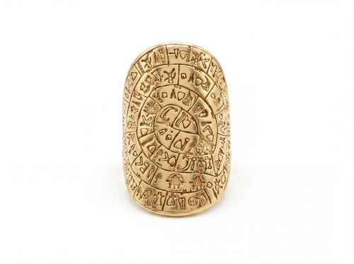 A gold-toned Aztec calendar ring featuring intricate engravings and glyphs, photographed on a clean white background.